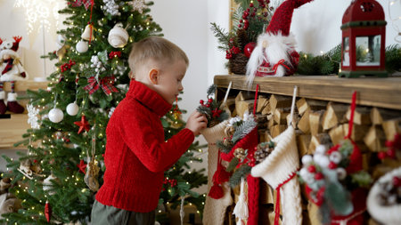 New year celebration concept. Boy and Christmas socks hanging on the fireplace. The boy looks into the New Years sock, which hangs by the fireplace. A young boy looks at a gift sock.の写真素材