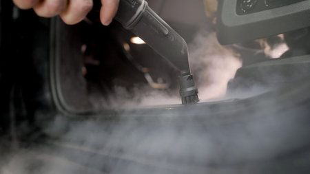 Steam car interior cleaning. Car wash, a worker cleans the thresholds of the car with a steam cleaner. Car interior cleaning.の写真素材