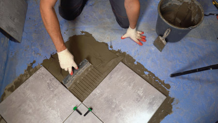 Process of laying floor ceramic tiles, application of the adhesive base. Application of adhesive -...