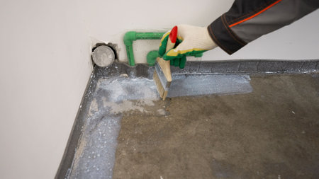 Floor waterproofing membrane on concrete floor. On the floor, the master applies white waterproofing. Floor waterproofing, hands close-up.の写真素材