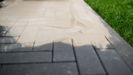DIY home improvement to back yard. Filling paving joints, Brushing dry sand. Finishing work. Sand mortar for paving stones.の写真素材