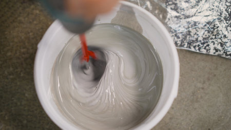 A man makes cement with a construction mixer in a bucket. Bucket with mortar at the construction...