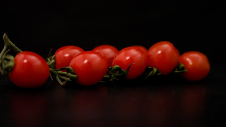 Delicious red cherry tomatoes rotate smoothly on a black wooden table close-up. Cherry tomatoes are spinning on the table.の写真素材