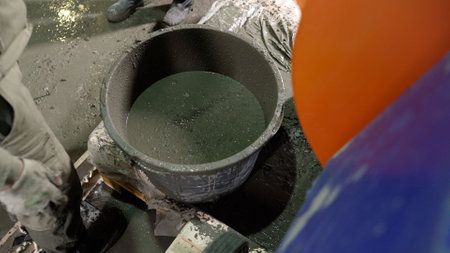 A worker pours a construction mixture into a bucket of water. Construction works. Add the dry mortar...