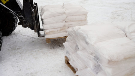 A forklift is loading large sacks of starch into a warehouse. Forklift in the winter on the street....