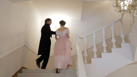 A couple in 19th century costumes. A man and a woman in 19th century costumes walk around the palace. The guy and the girl in the images of the 19th century climb the stairs.の写真素材