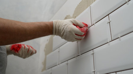 Tiles in the kitchen, the master glues. Workers lay ceramic tiles on the kitchen wall. Construction details, repair work.の写真素材