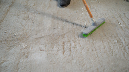 Builder with a brush removes construction debris. Builder collecting construction debris. House renovation.の写真素材