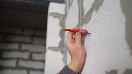 Before repairs, a worker makes marks on the wall with a pencil. The master takes measurements in the...