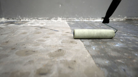 Primer of the floor with a roller, close-up. Concrete floor primer. The process of applying primer with a roller to a concrete floor. Primer for concrete floors to strengthen the surface.の写真素材