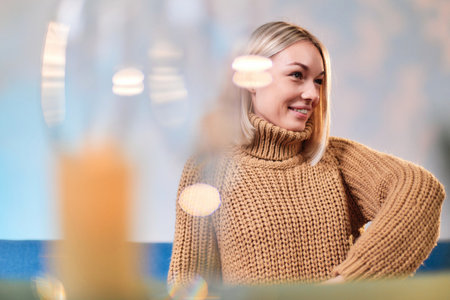 Person in a cozy sweater looking away with a cheerful expressionの写真素材