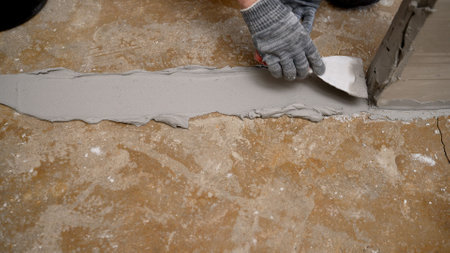 Construction worker applying cement on the floor using trowelの写真素材