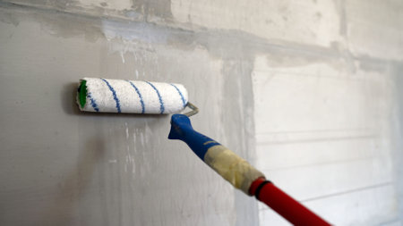 Construction worker applying plaster on the wall using a roller.の写真素材