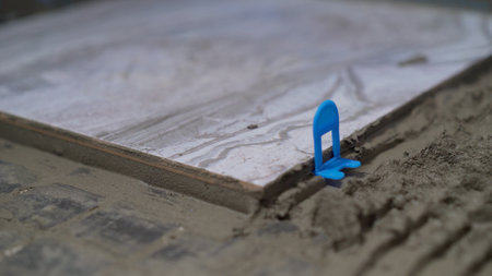 Construction worker is laying ceramic tile using a tile leveling system to ensure a perfectly level floor.の写真素材