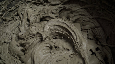 Construction worker mixes tile adhesive or cement in a bucket with a mixing drill, preparing materials for renovation projectsの写真素材