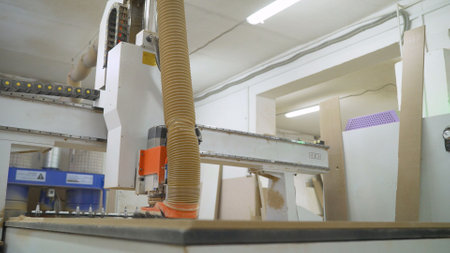Precision cnc router carving intricate wood panel within modern furniture manufacturing facility,...