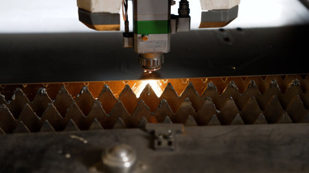 Laser cutting machine precisely cuts through metal sheet, creating sparks and demonstrating advanced...