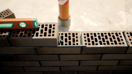 Skilled construction worker carefully laying bricks and applying mortar while building sturdy wall at residential development siteの写真素材