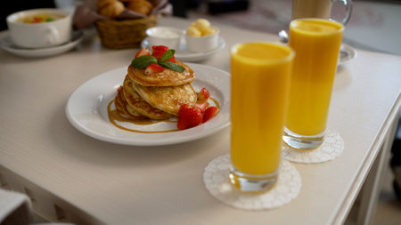 Delicious pancakes with strawberries and syrup served with orange juice for breakfast in bed at a hotelの写真素材