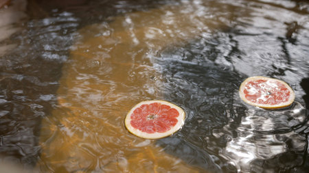 Grapefruit and orange slices gently move on the rippling water surface, creating a soothing and refreshing atmosphereの写真素材