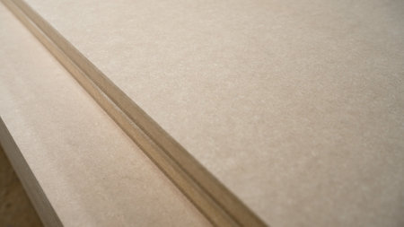 Close-up view of stacked particle boards, highlighting the texture and layers of the engineered wood...