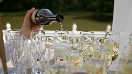 Golden sparkling wine being poured into a row of elegant glasses, creating a celebratory atmosphereの写真素材
