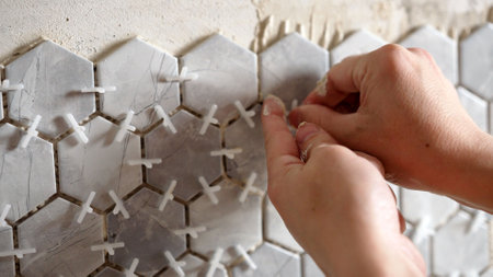 Tiler applying grout between hexagonal tiles on bathroom wallの写真素材
