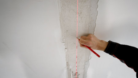Construction worker using laser level and pencil marking ceiling lineの写真素材