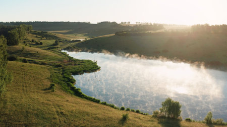 Sunlight gently illuminating green hills and pondの写真素材