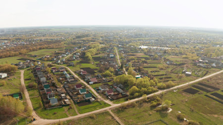 Aerial view of houses expanding into countryside with green fields and treesの写真素材