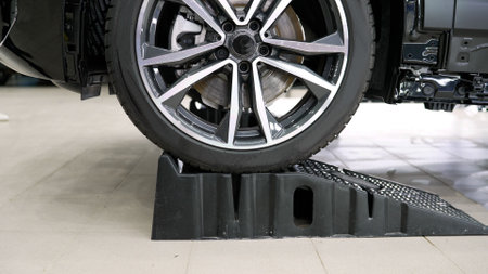 Car wheel positioned on plastic ramp inside auto repair shop, ensuring stability during maintenance