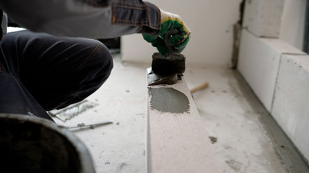 Construction worker spreading mortar on an aerated concrete block during building constructionの写真素材