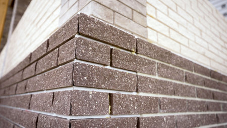 Construction of a brick wall. Workers building a two-colored brick wall on a construction site