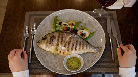 Grilled dorado fish served on a plate with vegetables and sauce, ready to be enjoyed in a restaurant...