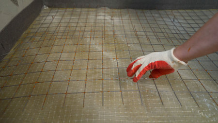 Construction worker laying fiberglass mesh on the floor, ensuring waterproofing before tiling in a...
