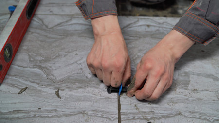 Construction worker uses a tile leveling system to ensure even tile spacing during installationの写真素材