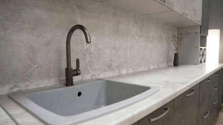 Stylish and contemporary kitchen featuring a marble countertop, backsplash, and a modern sink with faucetの写真素材