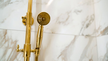 Elegant gold shower fixture set against a backdrop of polished marble tiles, showcasing luxury and modern bathroom designの写真素材