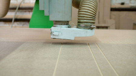 Automated cnc machine cutting precise grooves into a wooden board at a bustling furniture factory,...