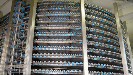 Spiral conveyor belt transporting goods in food processing plant