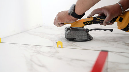 Construction worker placing marble tiles with tile leveling systemの写真素材
