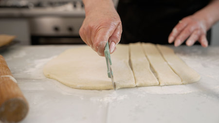 Baker cutting dough into strips in kitchenの写真素材
