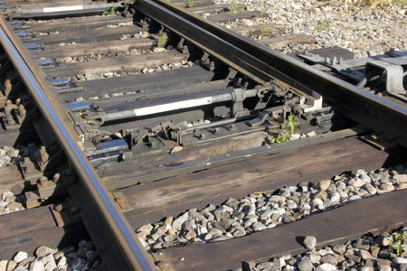 Close-up of a railroad switch mechanism connecting two tracks, highlighting the engineering and...