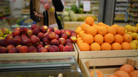Customer choosing fresh apples and oranges in supermarketの写真素材