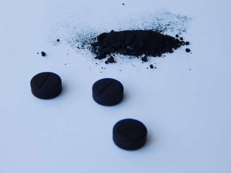 activated charcoal in tablets and in bulk on a white backgroundの写真素材