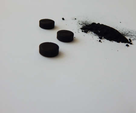 activated charcoal in tablets and in bulk on a white backgroundの写真素材