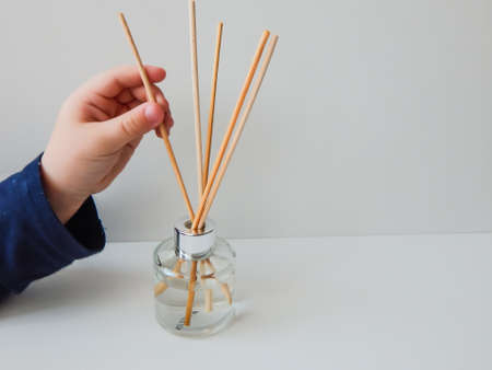 the child puts wooden sticks in a glass bottle with fragranceの写真素材
