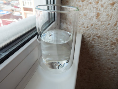 a glass of water by the window on the windowsillの写真素材