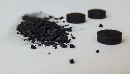 activated charcoal in tablets and in bulk on a white background