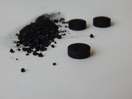activated charcoal in tablets and in bulk on a white backgroundの写真素材